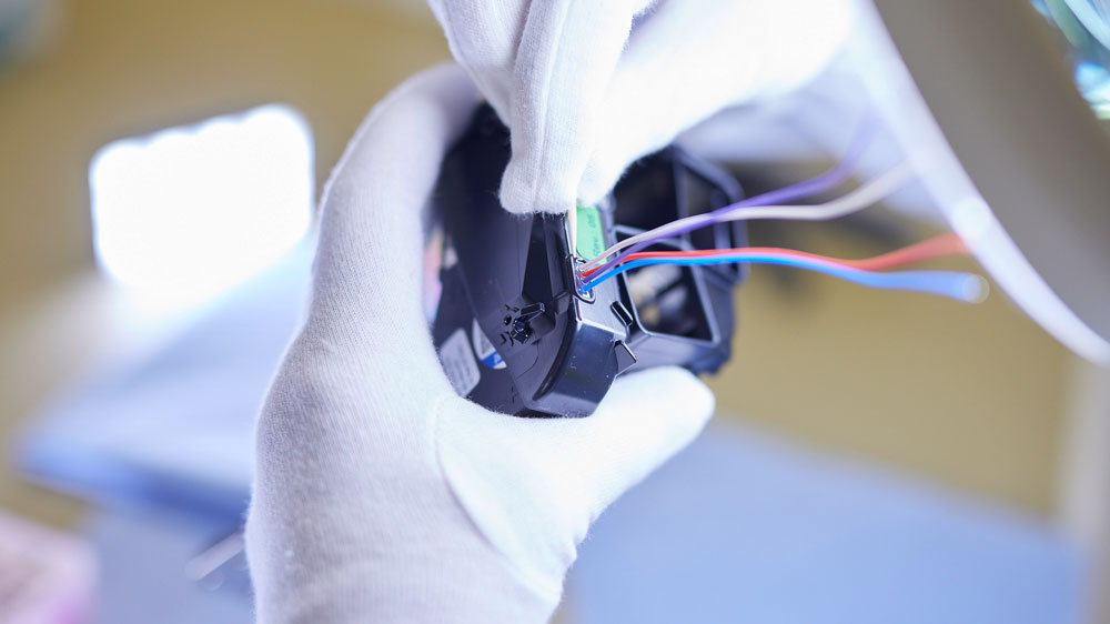 Hände mit weißen Handschuhen montieren elektronische Baugruppe